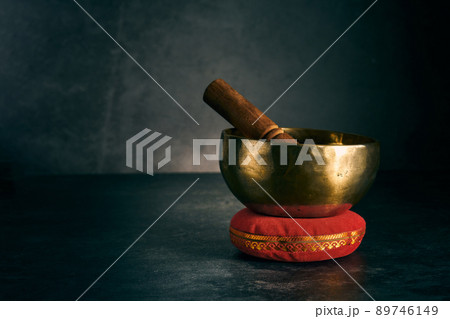 tibetan bowl on a red cushion in a dark background 89746149
