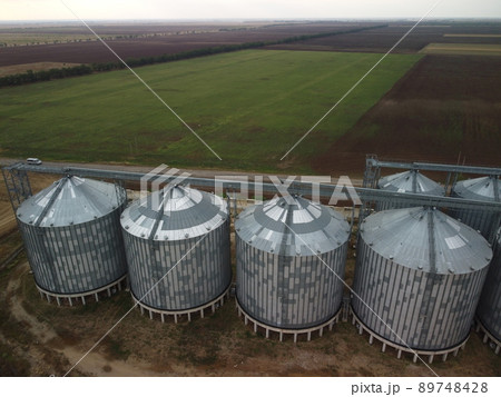 Grain elevator. Metal grain elevator in agricultural zone. Agriculture storage for harvest. Grain elevators on green nature background. Exterior of agricultural factory. Nobody. 89748428