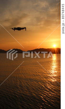 飛行中のドローンと夕日！SDGs地球の輝き　光りかがやく太陽と田舎の空と海の景色！ 89748445