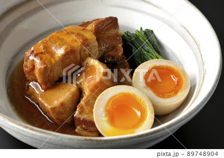 鉢に入った豚の角煮と半熟卵とホウレンソウを黒背景で撮影 89748904