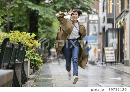 雨の中を走る若い女性 89751126