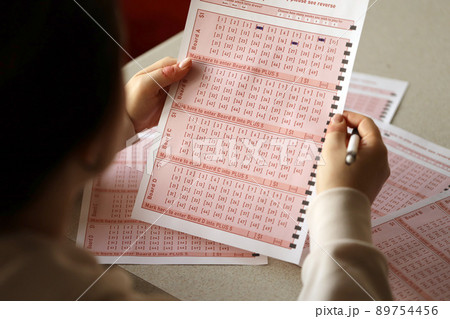 Filling out a lottery ticket. A young woman plays the lottery and dreams of winning the jackpot Filling out a lottery ticket. A young woman plays the lottery and dreams of winning the jackpot 89754456