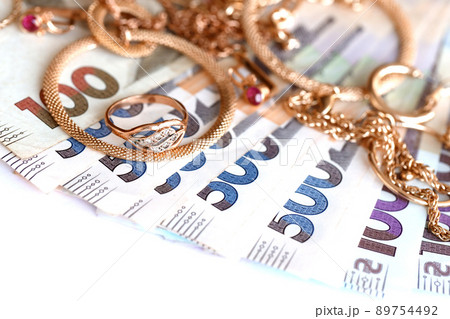 Many expensive golden jewerly rings, earrings and necklaces with big amount of Ukrainian money bills. Pawnshop or jewerly shop concept. Jewelry trading Many expensive golden jewerly rings, earrings and necklaces with big amount of Ukrainian money bills. Pawnshop or jewerly shop concept. Jewelry trading 89754492