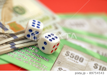 Close up view of green lottery scratch cards with us dollar bills and dice. Many used fake instant lottery tickets with gaming results 89754543