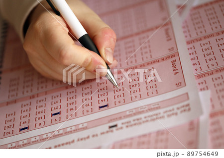 Filling out a lottery ticket. A young woman plays the lottery and dreams of winning the jackpot. Female hand marking number on red lottery ticket Filling out a lottery ticket. A young woman plays the lottery and dreams of winning the jackpot. Female hand marking number on red lottery ticket 89754649