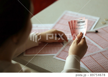 Filling out a lottery ticket. A young woman holds the lottery ticket with complete row of numbers on the lottery blank sheets background. Filling out a lottery ticket. A young woman holds the lottery ticket with complete row of numbers on the lottery blank sheets background. 89754678