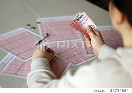 Filling out a lottery ticket. A young woman holds the lottery ticket with complete row of numbers on the lottery blank sheets background. Filling out a lottery ticket. A young woman holds the lottery ticket with complete row of numbers on the lottery blank sheets background. 89754684