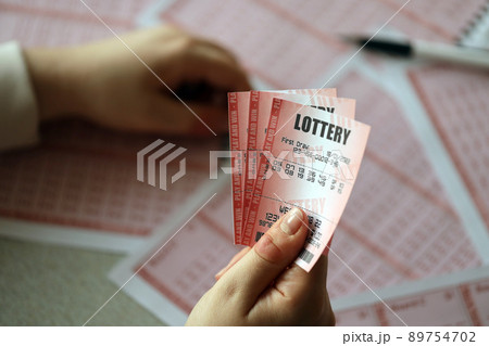 Filling out a lottery ticket. A young woman holds the lottery ticket with complete row of numbers on the lottery blank sheets background. 89754702