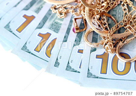 Many expensive golden jewerly rings, earrings and necklaces with big amount of US dollar bills on white background. Pawnshop or jewerly shop Many expensive golden jewerly rings, earrings and necklaces with big amount of US dollar bills on white background. Pawnshop or jewerly shop 89754707