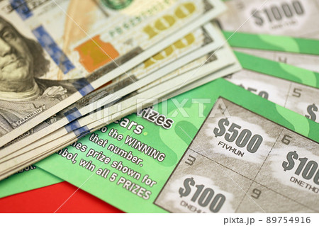 Close up view of green lottery scratch cards and us dollar bills. Many used fake instant lottery tickets with gambling results. Gambling addiction 89754916