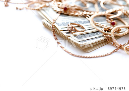 Many expensive golden jewerly rings, earrings and necklaces with big amount of US dollar bills on white background. Pawnshop or jewerly shop Many expensive golden jewerly rings, earrings and necklaces with big amount of US dollar bills on white background. Pawnshop or jewerly shop 89754973