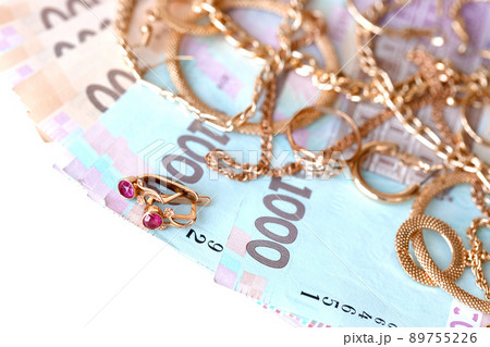Many expensive golden jewerly rings, earrings and necklaces with big amount of Ukrainian money bills. Pawnshop or jewerly shop concept. Jewelry trading Many expensive golden jewerly rings, earrings and necklaces with big amount of Ukrainian money bills. Pawnshop or jewerly shop concept. Jewelry trading 89755226