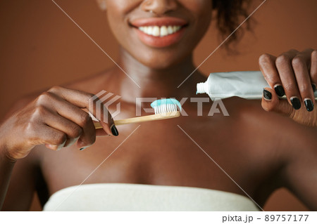 Woman Squeezing Toothpaste on Brush 89757177
