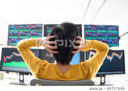 マルチモニターのチャートを見ながら頭を抱える男性の後姿　トレーダー　イメージ 89757690