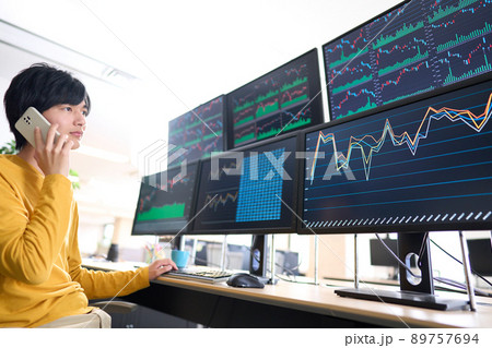 マルチモニターの画面を見ながらスマホで通話する個人投資家　トレーダー　イメージ 89757694