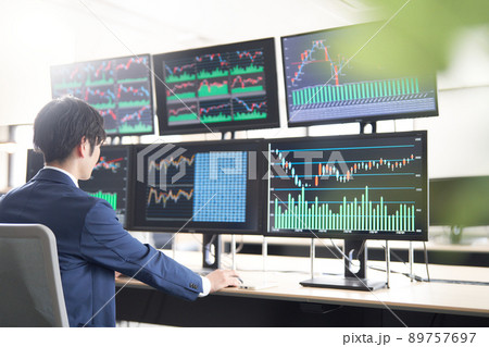 マルチモニターのPCの前に座るビジネスパーソン　トレーダー　イメージ 89757697