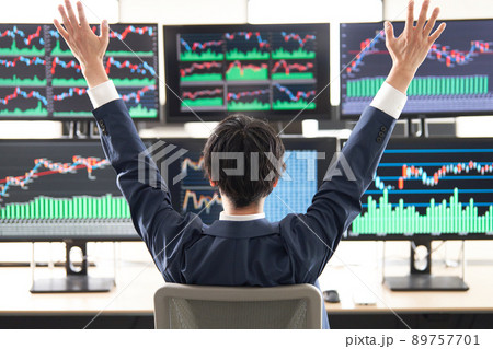 マルチモニターの画面を見ながら両手を挙げる男性の後姿　トレーダー　イメージ 89757701