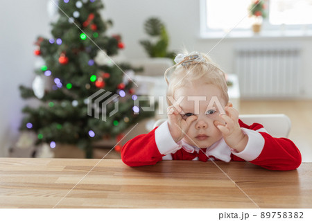 Child girl dressed in christmas dress with cochlear implants having fun at home with christmas tree background and copy space - hearing aid and innovating technologies for treatment of deafness 89758382
