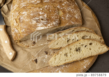 White sliced bread and knife. A loaf of bread with the first half already cut. Three slices of sliced bread. View from above. White sliced bread and knife. A loaf of bread with the first half already cut. Three slices of sliced bread. View from above. 89758879