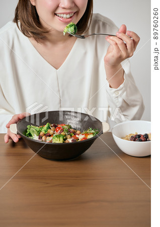 サラダとオートミールを食べる若いヴィーガン女性 89760260