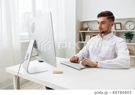 handsome businessman sitting at a desk in front of a computer with a keyboard technologies 89760805