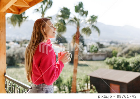 Young woman enjoying the view from apartment,drinking morning coffee on the balcony. 89761745