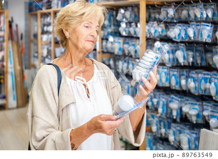 Elderly woman choices energy saving lamp at hardware store 89763549