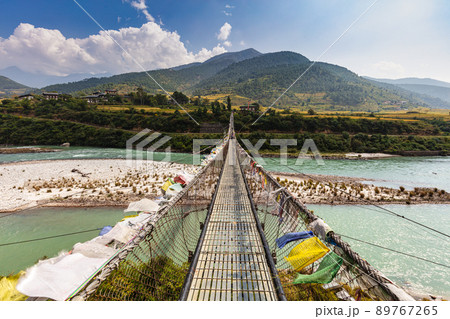 The Punakha Suspension Bridge at the Punakha Dzong. Across the Tsang Chu River to Shengana and Wangkha village. The longest suspension bridge in Bhutan and always decorated with colorful prayer flags. 89767265