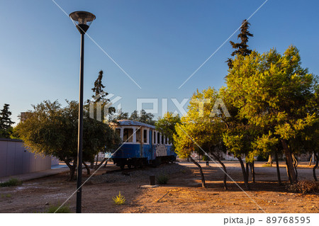 Lavrio, Greece - July 28, 2021: Old tram in a park in Lavrio. Covered in graffiti and without window glass. Discarded tram between trees in a park. Museum piece of former Public transport 89768595