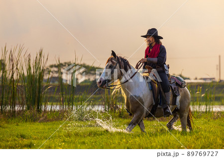 Cowboys riding horses beside the river and lifestyle with natural light background. 89769727