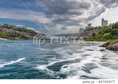 Niagara Falls, Canada - August 27, 2021: View of the impressive Niagara Falls. Horseshoe falls from the Canadian side . Massive water falls under the cloudy sky. Spume of the splashing water 89769977