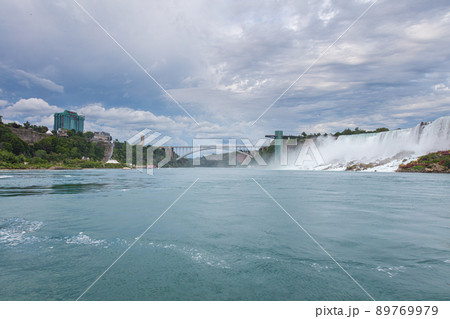 Niagara Falls, Canada - August 27, 2021: View of the impressive Niagara Falls. Horseshoe falls from the Canadian side . Massive water falls under the cloudy sky. Spume of the splashing water 89769979