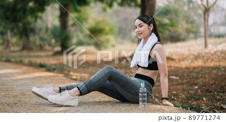 Athletic asian woman resting after a hard training in the mountains at sunset. Sport tight clothes Athletic asian woman resting after a hard training in the mountains at sunset. Sport tight clothes 89771274