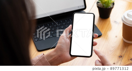 Top view Woman sitting on work desk and holding blank screen mock up mobile phone. Top view Woman sitting on work desk and holding blank screen mock up mobile phone. 89771312