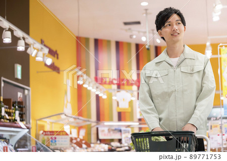 スーパーで買い物をする作業服姿の若い男性 89771753