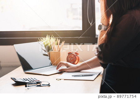 female accountant using calculator and typing on laptop.  89771754