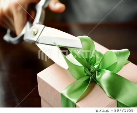 Decorating gift box with green ribbon using scissor Decorating gift box with green ribbon using scissor 89771959