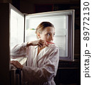 Young woman looking for some snack in fridge late at night 89772130