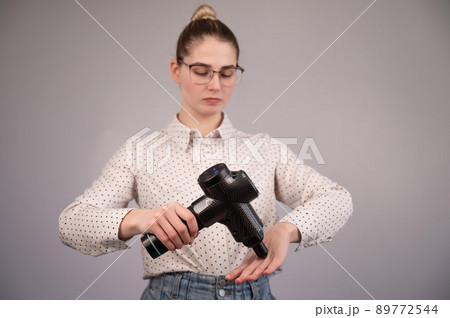 Caucasian business woman massaging her wrist with a percussion massager. 89772544