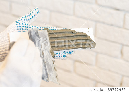 Professional Builder gluing decorative tile on wall. worker mounts decorative brick on wall 89772972