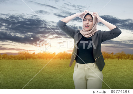 Asian Muslim woman in a headscarf feeling headache 89774198