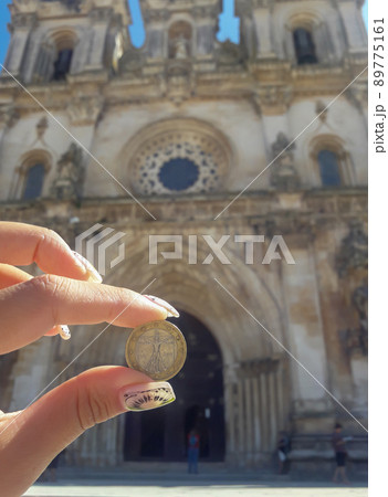 hand holding a coin with image of Vitruvian Man on the background of an old building hand holding a coin with image of Vitruvian Man on the background of an old building 89775161
