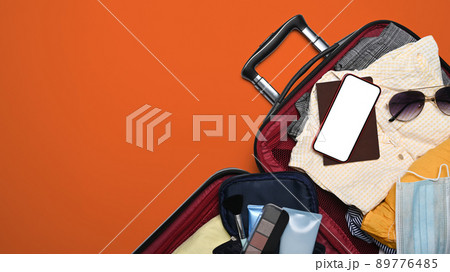 Smart phone, passport and clothes in suitcase. Preparing for the summer vacations Smart phone, passport and clothes in suitcase. Preparing for the summer vacations 89776485