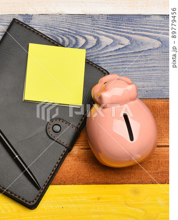 Moneybox with pig face near organizer and pen. 89779456