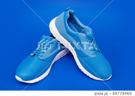 pair of comfortable sport shoes. sporty blue sneakers. shoes on blue background. pair of comfortable sport shoes. sporty blue sneakers. shoes on blue background. 89779469