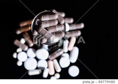 Starch capsules gel caps medication in glass dark background, caplets 89779480