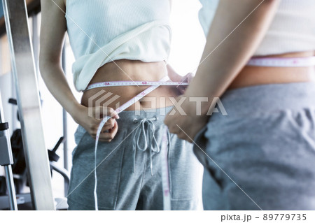 メジャーでウエストを測る若い女性 89779735