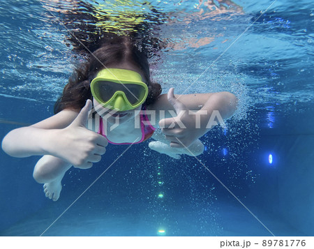 Smiling child in goggles swim, dive in the pool with fun - jump