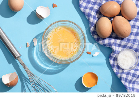 Beaten eggs on blue background. Flat lay. Beaten eggs on blue background. Flat lay. 89782019