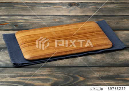Wooden board with kitchen napkin on dark wooden table 89783255